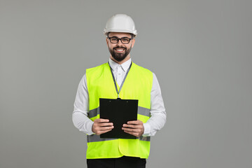 Wall Mural - Engineer in hard hat holding clipboard on grey background