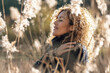 © simona - One woman in love for nature. Sustainability and environment concept people lifestyle. Curly female hugging herself in a golden field of grass in sunset light. People in outdoor leisure activity life