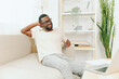 © SHOTPRIME STUDIO - African American man working on a laptop in a modern home office, sitting comfortably on a sofa With a smiling face, he is focused on his work, utilizing technology and cyberspace to complete his job
