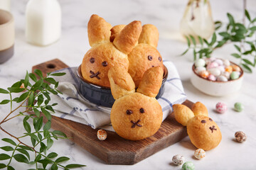 Canvas Print - Buns made from yeast dough in a shape of Easter bunny, and colored candy eggs. Traditional Easter symbols and food. Selective focus.