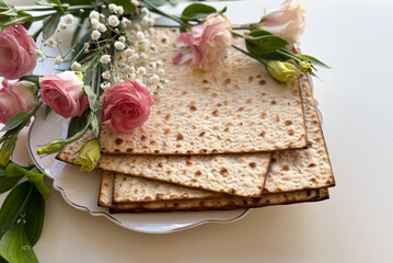 Wall Mural - Passover. Holiday of Jewish people. Traditional Matzo prepared for Passover decorate by flowers on white background. top view. Spring Holiday. Fasting time