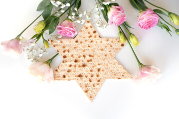 Wall Mural - Passover. Traditional Matzo shape of star Magen David  decorate by pink flowers on white background. top view. Holiday of Jewish people, Spring Holiday. Fasting time