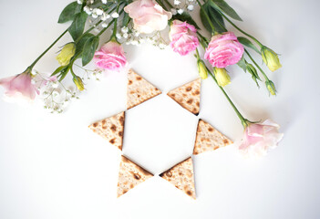 Wall Mural -  Passover.  Traditional Matzo shape of star Magen David decorate by pink flowers on white background. top view. Holiday of Jewish people, Spring Holiday. Fasting time