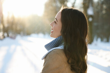 Canvas Print - Portrait of smiling woman in sunny snowy park. Space for text