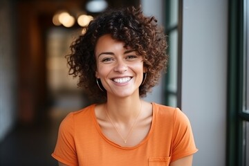 Wall Mural - Portrait of a smiling young woman with curly hair looking at camera