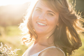 Smiling woman with flying hair at summer sunset.