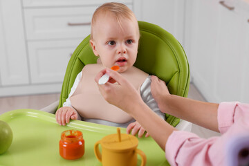 Mother feeding her cute little baby with healthy food at home