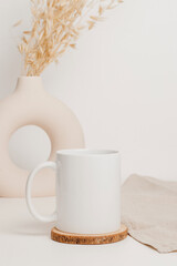 Wall Mural - White mockup mug on wooden cup coaster with linen cloth and stylish vase at the background . Mockup mug for logo, branding, print, gift and design. Scandinavian home interior, bohemian style