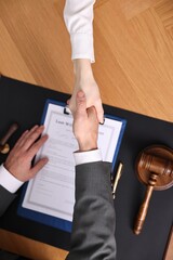 Wall Mural - Notary shaking hands with client at wooden table, top view