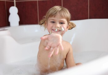 Canvas Print - Smiling girl showing bubble in bathtub at home, selective focus