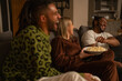 © Cultura Creative - Laughing friends relaxing on sofa at home, sharing popcorn
