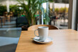 A Cup of freshly brewed black tea at a cafe blurred background. Coffee cup on table cafe shop Interior. Concept of easy breakfast. One white big ceramic cup. Top view. Mock up