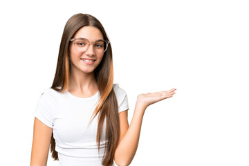 Wall Mural - Teenager caucasian girl over isolated background holding copyspace imaginary on the palm to insert an ad