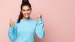 Young strong sporty athletic fitness trainer instructor woman wear blue tracksuit spend time in home gym show thumb up gesture blink isolated on pastel plain pink background. Workout sport concept.