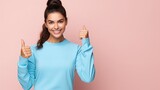 Fototapeta  - Young strong sporty athletic fitness trainer instructor woman wear blue tracksuit spend time in home gym show thumb up gesture blink isolated on pastel plain pink background. Workout sport concept.