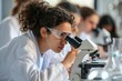 © darshika - College students conducting microscope experiment in science lab.