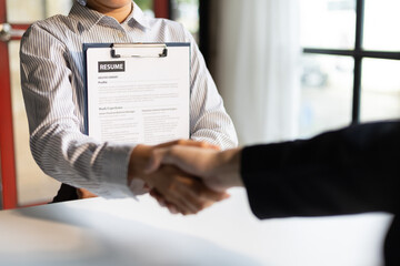 Wall Mural - Business, career and placement concept - image of employer sitting in office and shaking hand of young asian woman after successful negotiations or interview.