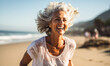 Joyful senior woman with white hair running on the beach, embodying active aging and wellness with a bright smile, in a coastal morning fitness routine