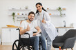 © sofiko14 - Portrait of female doctor hugging smiling male patient with disability posing at home at background of light kitchen. Health professional giving recommendation and care about treatment .