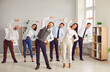 © Studio Romantic - Happy young business people doing stretching sport exercises standing together in modern office. Group of smiling company employees exercising fitness for health during a break from a work.