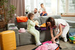 © master1305 - Little girl sitting on couch and putting clothes to bag and woman trying to close luggage while man and boy booking tickets and hotel for rest online. Concept of tourism, holiday, vacation, relaxation