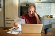 © Marko Geber - Stressed man going over bills at home