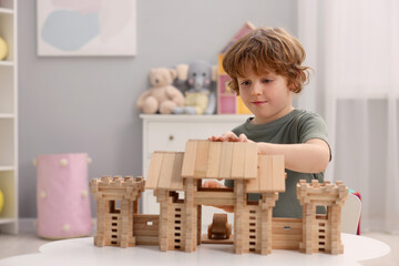 Wall Mural - Little boy playing with wooden entry gate at white table in room, space for text. Child's toy