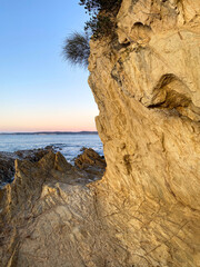 Wall Mural - Sunrise over yellow mountains near the water. Rocks on the ocean beach. Dawn on the beach. Rocky shoreline at sunset.