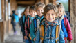 Smiling boy closeup with backpack and blue anorak filing into school building followed by more children. Primary school returns to classes after the holidays. Elementary teaching concept. Ai generated