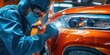A man in a blue uniform is working on a car. Suitable for automotive industry or car repair-related content