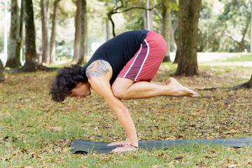 a man doing yoga bakasana pose in the park