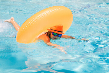 Poster - Child in swimming pool on inflatable ring. Kid swim with orange float. Kids beach fun.