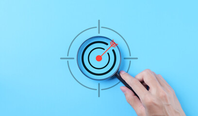 Wall Mural - Business goals and target success concepts. Holding a magnifying glass with bullseye icon. Aim business, Business Growth, Goal objective strategy plan action, Target success, achievement company,