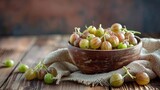 Ripe gooseberries fruit in bowl with sackcloth on wood table 
