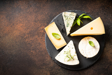 Sticker - Cheese platter with craft cheese assortment on slate board at stone table. Flat lay.