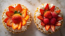  Two Cupcakes With Strawberries On Top Of Them On A Marble Counter Top With White Frosting And A Marble Slab Of Counter Top With A Marble Counter Top.