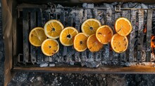  A Grill Filled With Lots Of Oranges On Top Of A Metal Grate Next To A Pile Of Burnt Wood And A Fire Pit With A Bunch Of Burnt Oranges On Top.