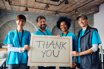 Wall Mural - Multiracial group of happy volunteers holding placard with 'Thank you' message and looking at camera.