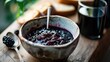  a bowl of blueberry compote on a cutting board with a spoon and a glass of blackberries.