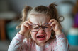 A child refusing to wear her glasses. She is crying and taking off her glasses, expressing her discomfort and dislike for them. --ar 3:2 --v 6 Job ID: 917fd81e-8f0f-4bff-94e9-b7d2427ad8ec