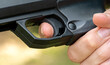 Detailed close-up of a persons index finger placed on the trigger of a black handgun, anonymous man ready to fire a simple sport firearm, air gun, firing a weapon. Gun safety rules, sports and weapons