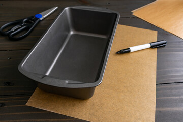 Loaf Pan with Parchment, Kitchen Scissors, and a Marker: Rectangular bread pan with supplies to trim baking paper to fit to line the inside