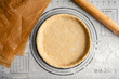© Candice Bell - Unbaked Pastry Dough in a Tart Pan: Raw pie crust in a fluted pan on a floured work surface with a French rolling pin and unbleached parchment paper
