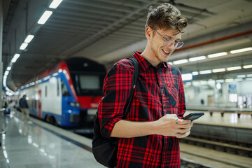 Wall Mural - Man commuting to work or a school by a train or a subway while using a phone