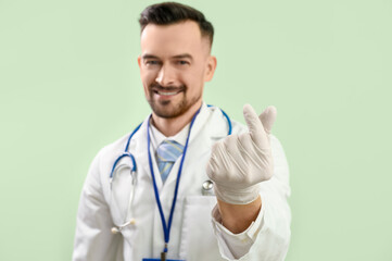 Sticker - Male doctor making heart with his fingers on green background, closeup