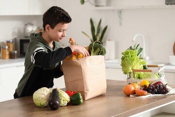 Sticker - Cute little boy and paper bag with different vegetables in kitchen