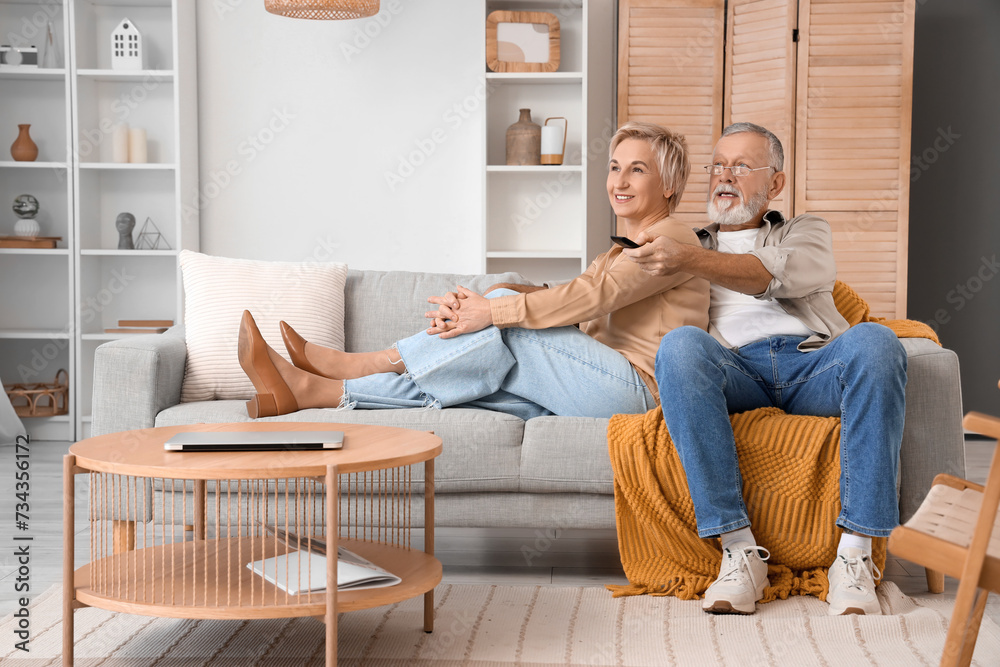 Mature couple watching TV on sofa at home