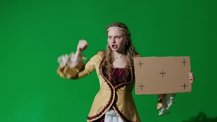 Wall Mural - Woman in ancient outfit on chroma key green screen background. Female in renaissance style dress holding cardboard sign talking advertising service