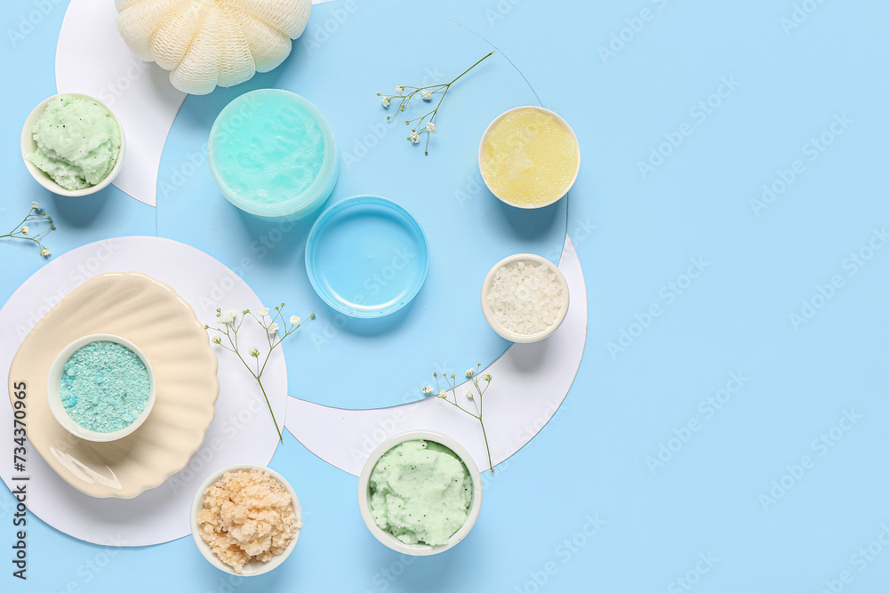 Scrubs with sea salt, sponge and flowers on blue background. Body massage concept