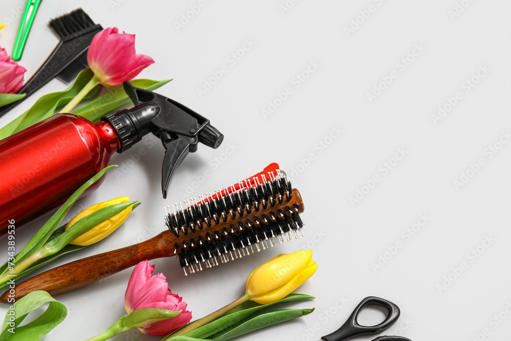 Hairdresser's tools with beautiful tulips on grey background
